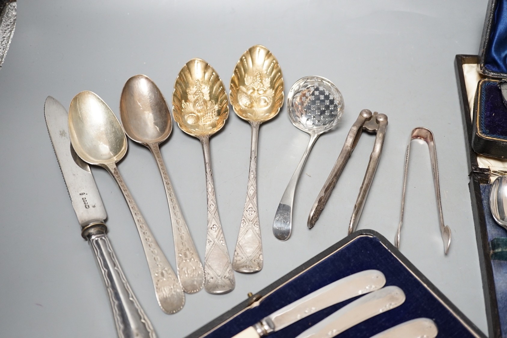 Two pairs of 18th century silver tablespoons including 'berry', a George III silver sifter spoon, pair of sugar tongs and other items including cased plated sets.